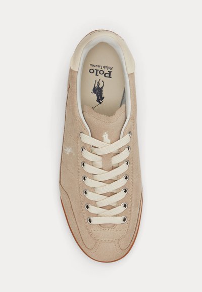 Baskets en daim beige avec lacets blancs, logo Polo Ralph Lauren blanc sur la languette et logo joueur de polo noir sur la semelle intérieure.