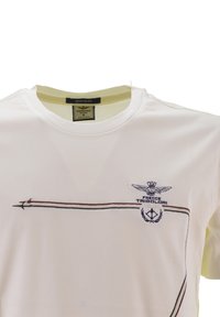 T-shirt di cotone bianco con colletto rotondo, maniche corte e logo ricamato con linee verdi e rosse e un emblema blu sul petto.
