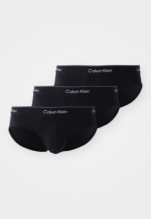 Három pár fekete pamut alsónadrág fehér "Calvin Klein" elasztikus derékpánttal. Mindegyik pár klasszikus, szoros illeszkedésű és sima szövet textúrájú.