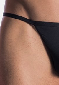Schwarze Männer-Bikiniunterwäsche, mit glatter Textur, minimaler Abdeckung, dünnen Seitenbändern und einem eleganten Design für eine körpernahe Passform.
