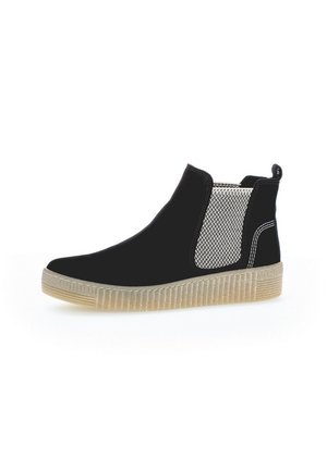 Black Chelsea ankle boot with beige textured elastic side panel, pull tab at heel, white stitching, and translucent ribbed rubber sole.