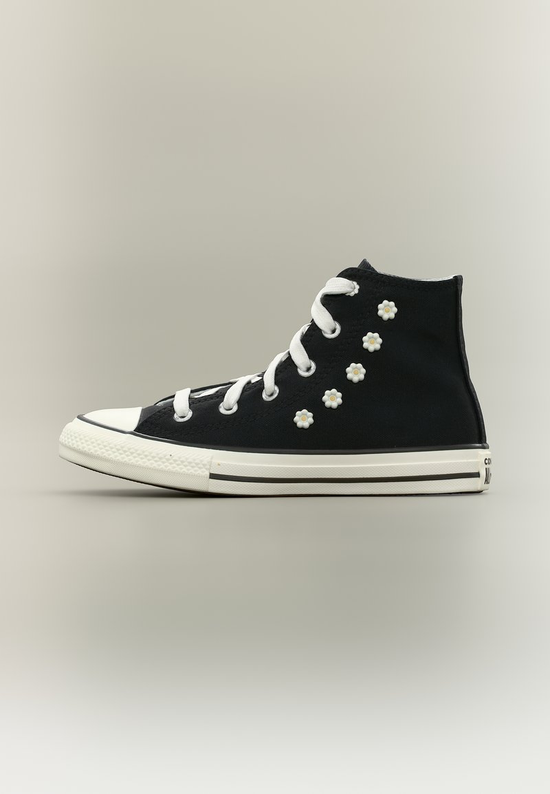 Μαύρο ψηλό αθλητικό παπούτσι με λευκή σόλα και κορδόνια, διακοσμημένο με έξι μικρά λευκά στολίδια σε σχήμα λουλουδιού στη πλευρά.