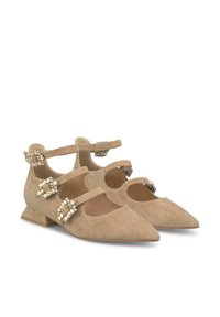 Ballerines en suède beige avec des bouts pointus, dotées de côtés découpés et de deux brides à la cheville ornées de boucles décoratives et de strass.