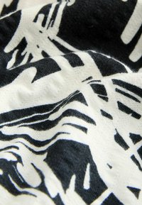 Stoff mit schwarz-weißen abstrakten Mustern, der eine weiche Textur, eine gewellte Oberfläche und unterschiedliche Linienstärken aufweist.