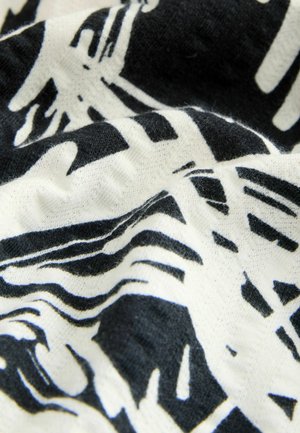 Fekete és fehér absztrakt mintázatú textil, lágy tapintással, hullámos felülettel és változó vastagságú vonalakkal.