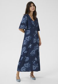 Sötétkék virágmintás maxi ruha rövid fodros ujjakkal, mély V-kivágással és világoskék virágmintázattal az egész felületen. Simább textúrájú.