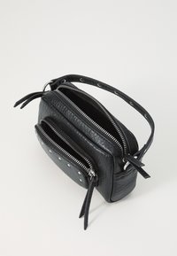 Černá kožená crossbody taška s dvojitými zipovými přihrádkami, dekorativními stříbrnými cvočky a texturovaným povrchem. Obsahuje úzký nastavitelný popruh.