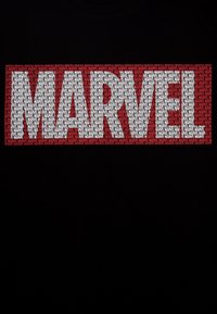 T-shirt nera con un grande e audace logo "MARVEL" in testo rosso e bianco, circondato da testo ripetuto più piccolo in vari colori.