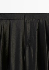 Zwarte plissérok gemaakt van glanzende stof, voorzien van een gladde bovenband en verticale plooien voor een gestructureerde uitstraling.