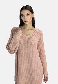 Gestrickter Pullover in sanftem Blush-Pink mit lockerer Passform, weiten Ärmeln und V-Ausschnitt, der ein strukturiertes, atmungsaktives Stoffmuster aufweist.