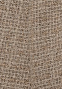 Gelaagd geweven stof in tinten beige, met een strak rasterpatroon en variërende vezeldiktes en subtiele kleurvariaties.