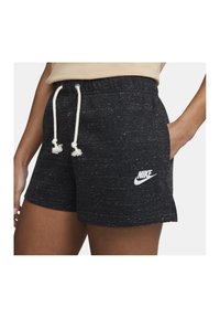 Svarta, prickiga shorts med dragsko i midjan och vitt Nike-logotyp. Tyg med mjuk struktur och sportig passform.