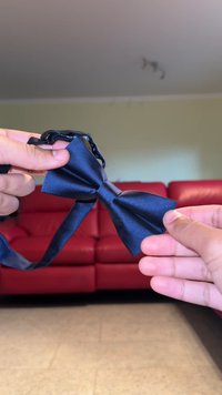 Sötétkék selyem előkötő, sima textúrával, klasszikus pillangó formával, fekete pánttal a kényelmes viselhetőség érdekében.