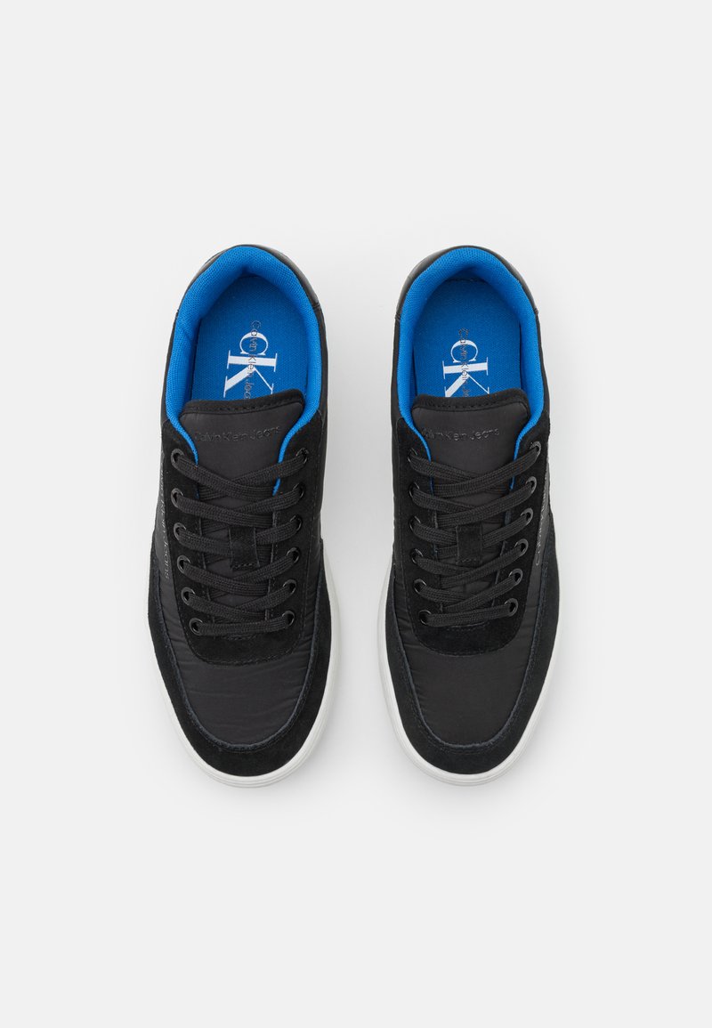 Baskets noires avec une tige texturée, dotées d'accents et de lacets bleus. La semelle intérieure est d'un bleu vif, affichant le logo de la marque.