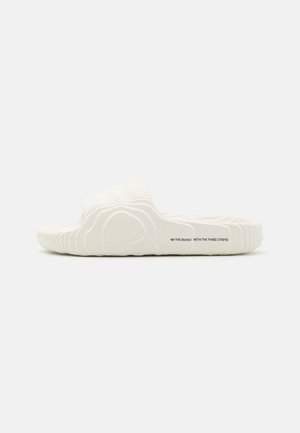 Białe sandały wsuwane z teksturowanym, topograficznym wzorem oraz napisem „The Brand With The Three Stripes” na bocznej podeszwie.