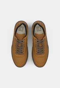 Brown perforated leather sneakers with dark gray laces, rounded toe, and signature logo on the tongue. Rubber sole with contrasting color accents.