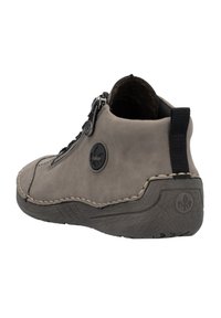 Botte ankle en suède gris avec une semelle en caoutchouc texturée, fermeture éclair sur le côté et accents en cuir noir. Présente un logo circular proéminent sur le côté.