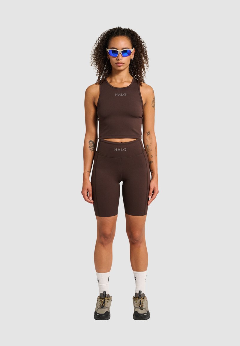 Braunes sportliches Tanktop und Shorts-Set mit "HALO"-Logo. Hat ein figurbetontes Design und wird mit grauen und schwarzen Schuhen kombiniert, was den sportlichen Look unterstreicht.
