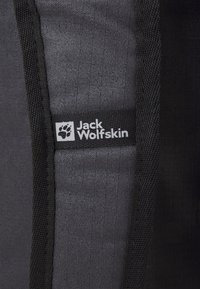 Czarna tkanina o gładkiej fakturze i wyraźnym znaku towarowym Jack Wolfskin. Posiada kontrastowe czarne szwy wzdłuż brzegów.