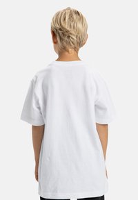 Biela bavlnená tričko s krátkymi rukávmi, voľného strihu a okrúhlym výstrihom, zobrazené zo zadnej strany. Hladká textúra, žiadne viditeľné logá ani vzory.