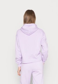 Lavendel hoodie med ribbade ärmar och nederkant, tillverkad av mjukt tyg. Något croppad design med en avslappnad passform.