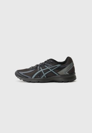Chaussure de course noire et gris foncé en tissu mesh, fermeture à lacets et semelle en caoutchouc, vue de profil sur un fond clair.