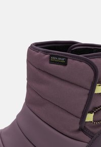 Botte waterproof violette avec un design rembourré, présentant une surface texturée, des accents jaunes contrastants et une étiquette KEEN.DRY®.
