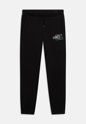 Pantalon de survêtement noir avec taille élastique, poches latérales et un logo imprimé coloré arborant "JACK & JONES". Matière en coton lisse, coupe fuselée.