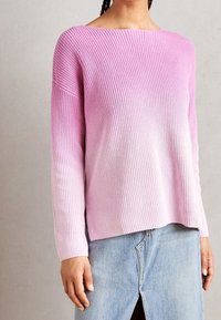 Roze ombre gebreide trui met ribbelstructuur, brede bootnek en lange mouwen. Gecombineerd met een lichte denimrok met een voorkeenspleet.