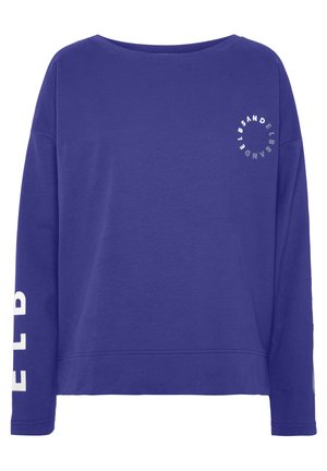 Fioletowa bluza z długim rękawem i okrągłym dekoltem, z białym okrągłym logo na piersi oraz częściowym białym napisem na lewym rękawie.