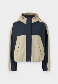 Veste à capuche avec un design en blocs de couleurs bleu marine et beige, poignets élastiques et deux poches à l'avant ; fabriquée à partir d'un matériau léger.