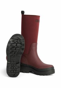 Röda vattentäta gummistövlar med en texturerad svart sula. Designen har en förstärkt ovandel, ett dragband vid hälen och en strömlinjeformad form.
