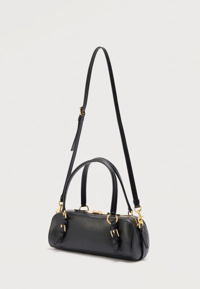Μαύρη ορθογώνια δερμάτινη τσάντα χειρός με διπλές λαβές, ρυθμιζόμενο μακρύ λουράκι ώμου, αγκράφες σε χρυσό τόνο και κλείσιμο με φερμουάρ.
