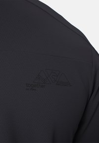 Tissu noir texturé avec un logo subtil montrant trois formes rappelant des montagnes et le texte « ensemble dehors » au dos.