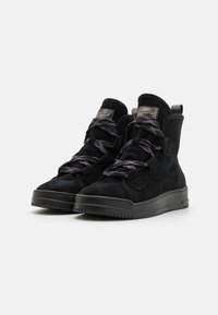 Sneaker alte nere in suede con lacci in tessuto, suola piatta e tallone rinforzato. Presentano cinghie decorative e un'etichetta in metallo con il logo.