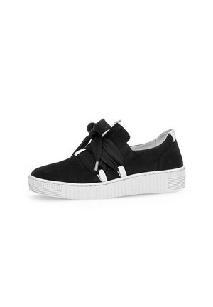 Black suede low-top sneaker with thick white rubber sole and wide black laces tied in a bow, displayed against white background.
