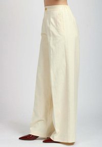 Pantaloni a gamba larga in tessuto crema, caratterizzati da un'alta vita, pieghe frontali e un dettaglio con bottone in vita. Texture liscia e pieno drappeggio.