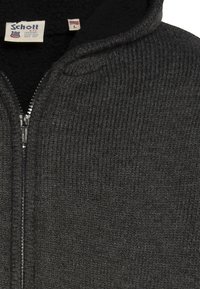 Ciemnoszara bluza z zamkiem, wykonana z teksturowanej tkaniny o żebrowanym wzorze. Posiada czarną polarową podszewkę oraz metkę z rozmiarem Large.