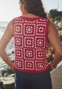 Rood gehaakt topje met een vierkant patroon met witte accenten, mouwloos ontwerp, textuurrijke afwerking en een gegolfde zoom.