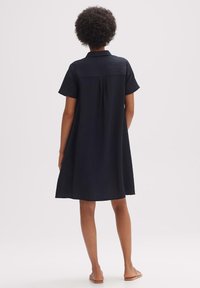 Kortärmad klänning i knälängd i mörk marinblå, med en texturerad tyg, krage och en avslappnad passform. Enkelt, eleganta design.