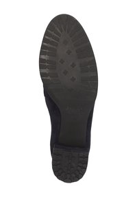 Semelle en caoutchouc noir avec une semelle texturée, présentant des motifs ovales et en losange, attachée à un dessus en suede de couleur bleu marine foncé.