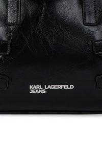 Μαύρη δερμάτινη τσάντα με ραμμένα χερούλια και ασημένιο λογότυπο "KARL LAGERFELD JEANS" στο κέντρο μπροστά.