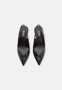 Los tacones slingback de cuero negro presentan un diseño de punta afilada, textura suave y lados recortados, con un logo de la marca en la plantilla.