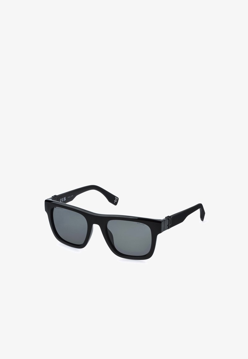Lunettes de soleil rectangulaires noires avec verres foncés et branches texturées inclinées sur un fond blanc.