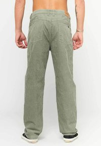 Pantaloni in corduroy verde con una vestibilità ampia, caratterizzati da righe verticali, tasche posteriori e un'etichetta in pelle sul waistband.