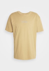 Béžové bavlněné tričko s krátkým rukávem, kulatým výstřihem a světle modrým potiskem loga na hrudi. Hladká textura, minimalistický design.