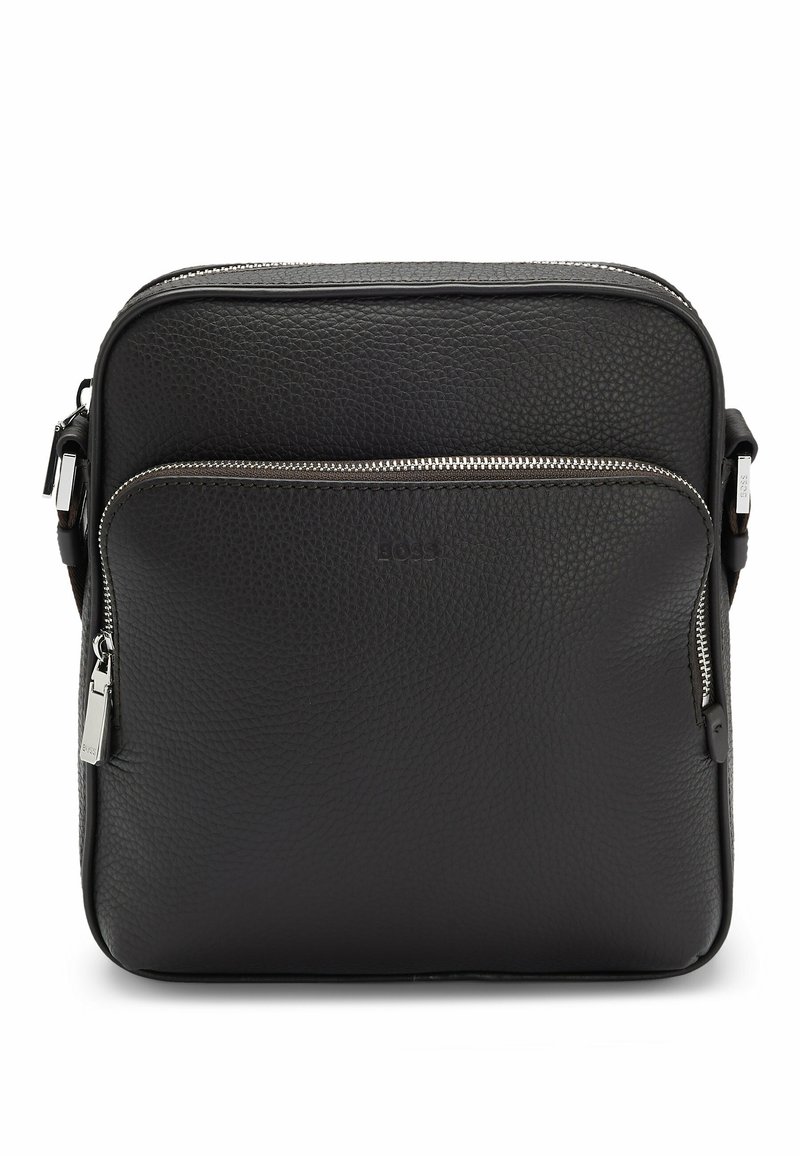 Sort læder crossbody taske med en tekstureret overflade, som har en for- lomme og sølv hardware, herunder en lynlåslukning og stropdetaljer.
