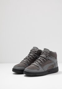 Baskets hautes grises en suède et matériaux synthétiques, avec des accents perforés, un col texturé et une semelle en caoutchouc.