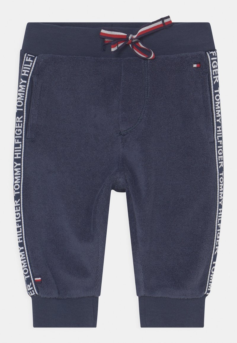 Pantalon pour tout-petit bleu marine avec taille élastique, cordon rouge-blanc-bleu, bandes latérales avec l'inscription "Tommy Hilfiger" et petits écussons logo.