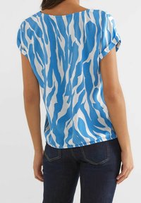 Top a maniche corte in stampa zebra blu e bianca. Realizzato in tessuto morbido con una vestibilità comoda e maniche arrotolate, presenta un collo rotondo.